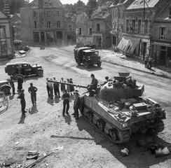 A Sherman Firefly and other vehicles in the village of Putanges, 20 August 1944